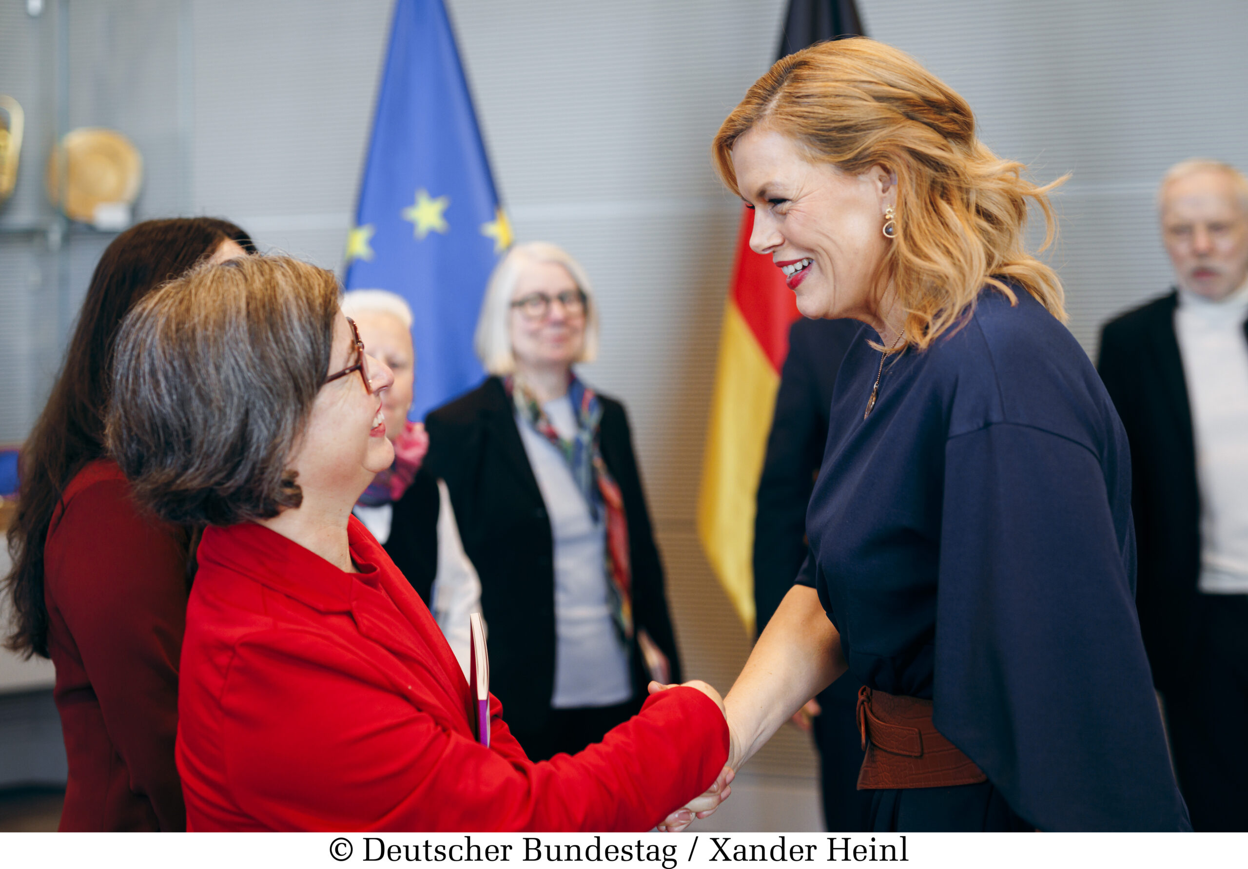 Julia Klöckner hat blonde schulterlange Haare und ein blaues Kleid an. Sie schüttelt Julia Gebrande die Hand. Julia Gebrande hat graue kurze Haare und trägt einen roten Blazer. 