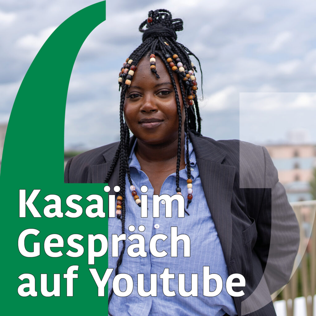 Foto einer jungen Schwarzen Frau mit Braids und einer blauen Bluse, darauf Grafik von Anführungszeichen und Text: "Kasai im Gespräch auf Youtube"