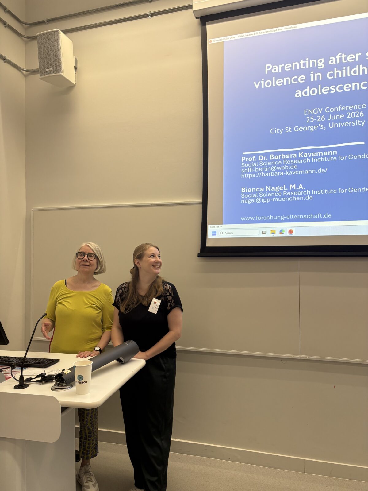 Auf dem Bild sind Barbara Kavemann und Bianca Nagel zu sehen. Sie stehen vor einer Leinwand auf der der Titel des Forschungsprojekts steht.