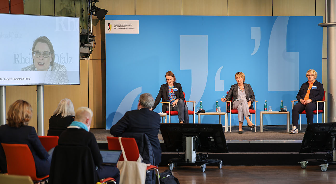 Blick auf das Podium mit Manuela Stötzel, Moderatorin Anke Plättner und Maike Finnern. Links großer Videobildschirm mit Stefanie Hubig